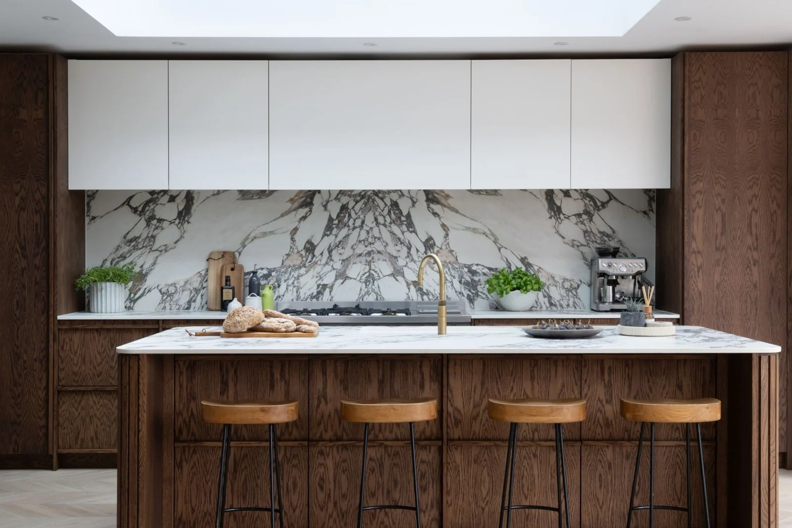 Dark oak kitchen island with curved slatted ends and dramatically veined porcelain